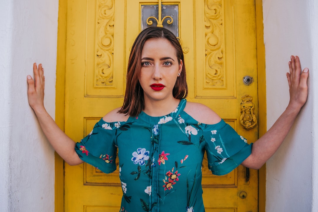 girl in blue and red floral dress standing near brown wooden door