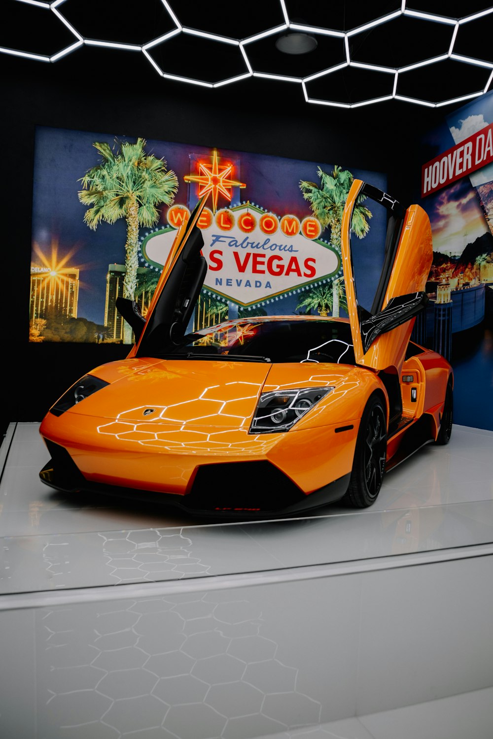 an orange sports car parked in front of a las vegas sign
