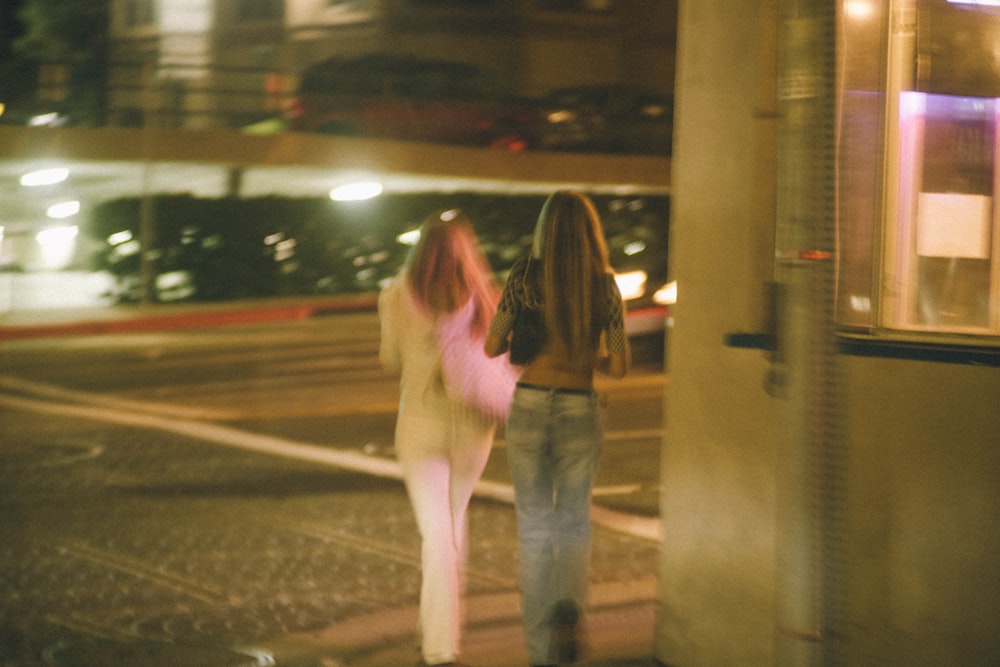 two women walking down a street at night