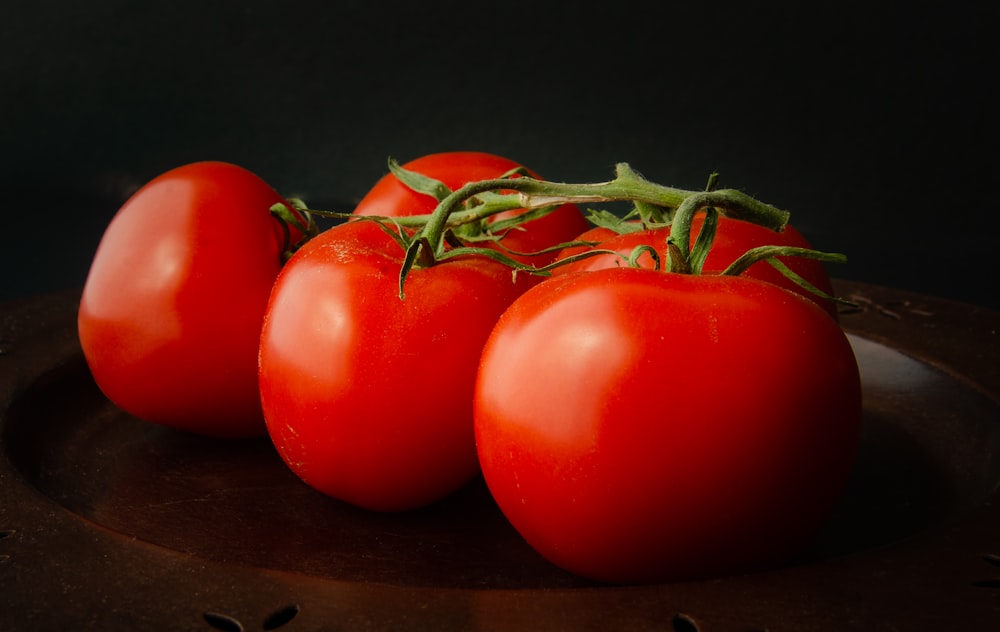 a group of four tomatoes sitting on top of a plate