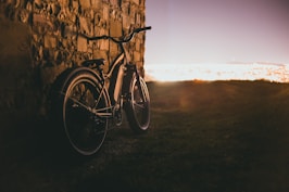 a bike leaning against a stone wall in the sun