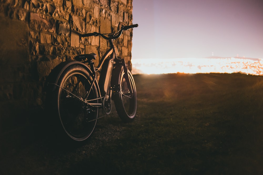 a bike leaning against a stone wall in the sun