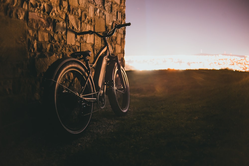 Una bicicleta apoyada contra una pared de piedra al sol