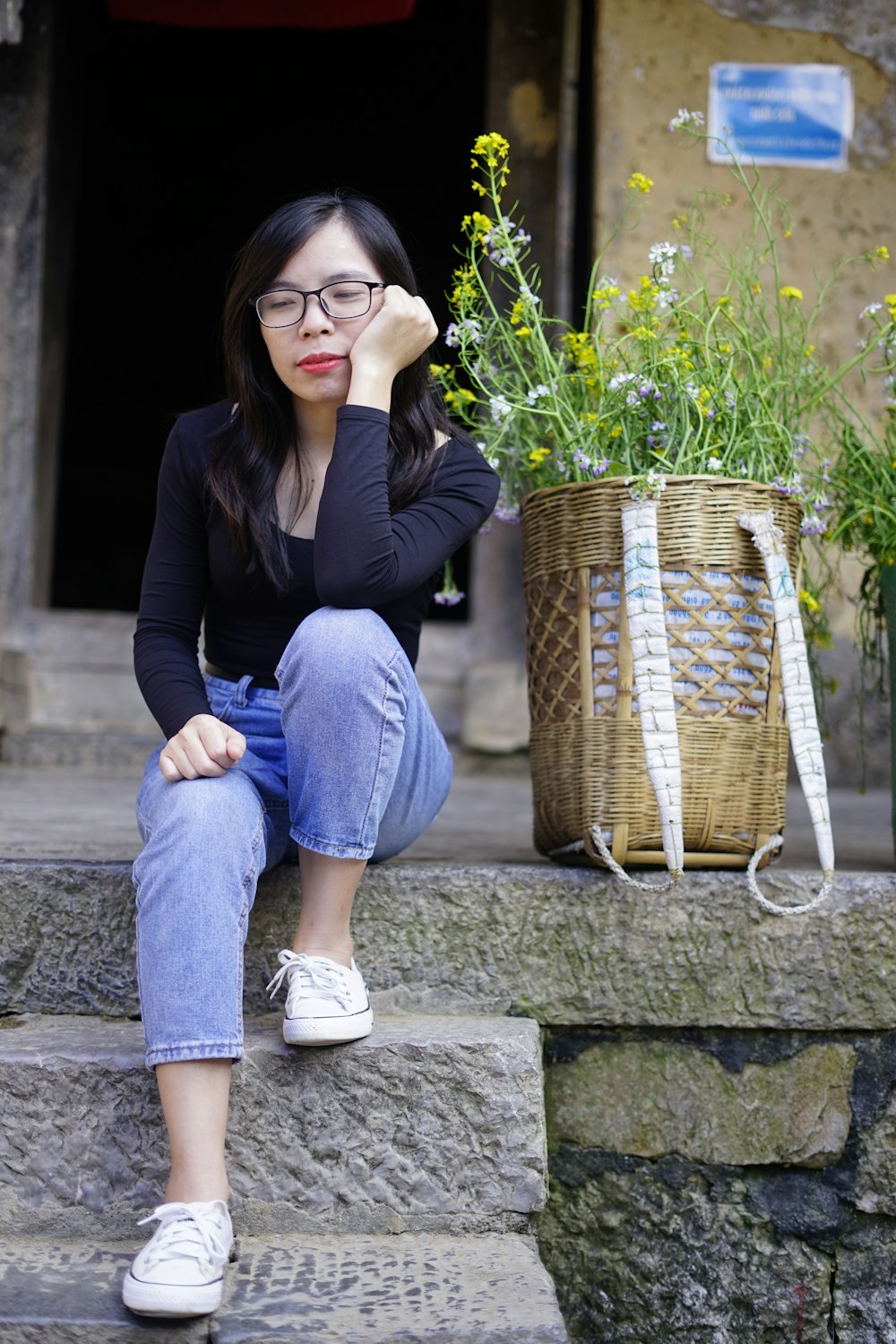 a woman sitting on steps with a basket of flowers