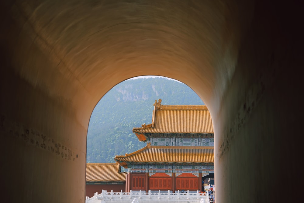 a tunnel leading to a building with a mountain in the background