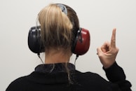a woman wearing headphones pointing to the side