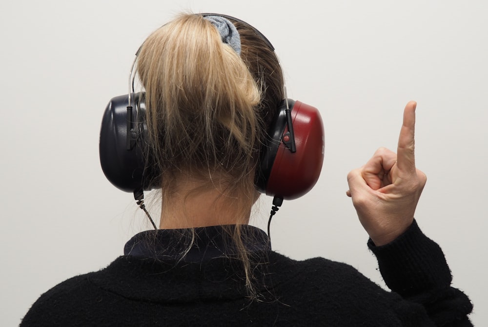 a woman wearing headphones pointing to the side