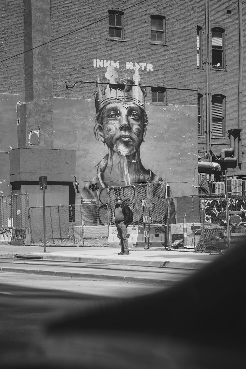 a black and white photo of a man walking past a building