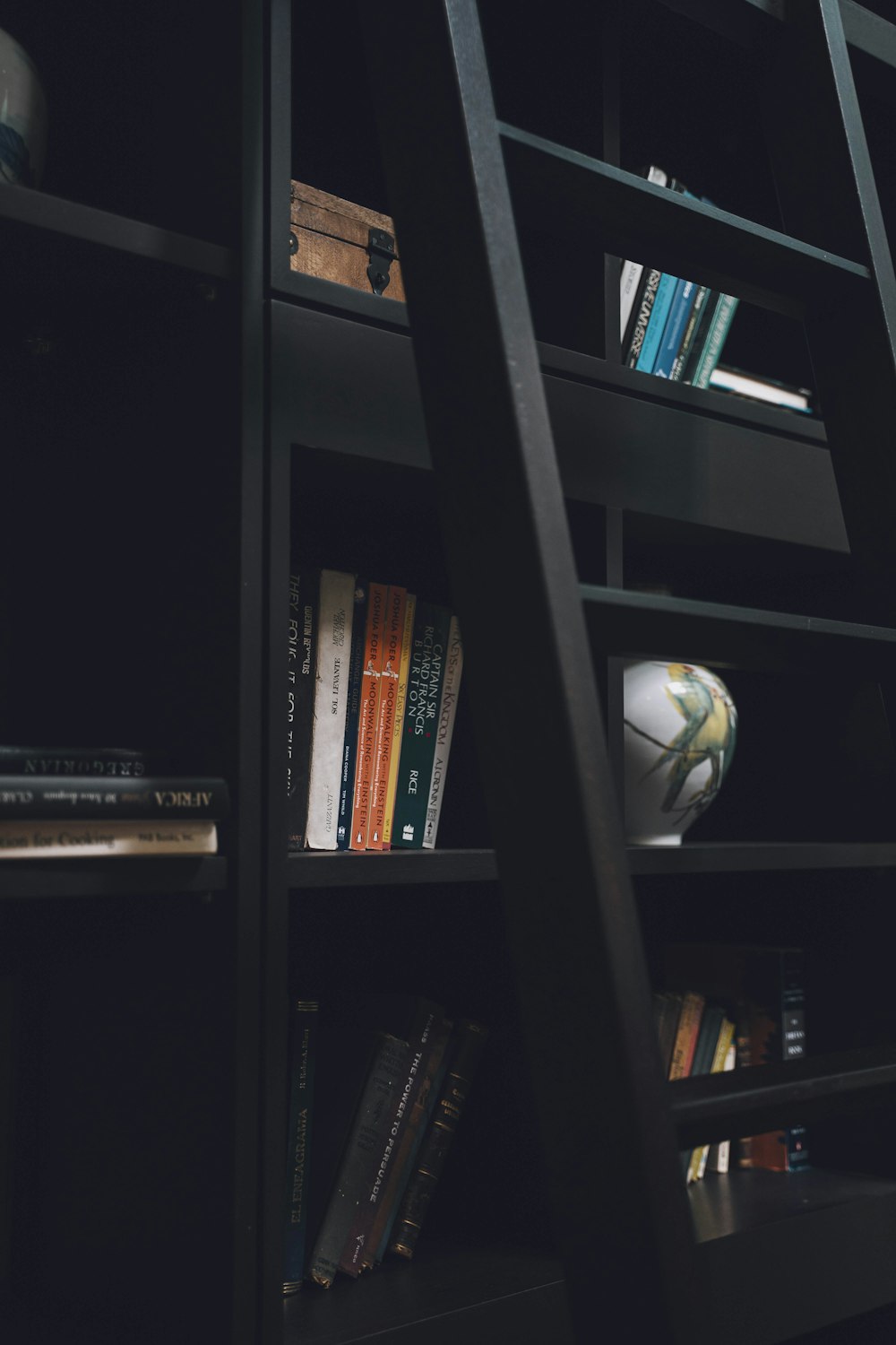 a bookshelf filled with lots of books next to a vase