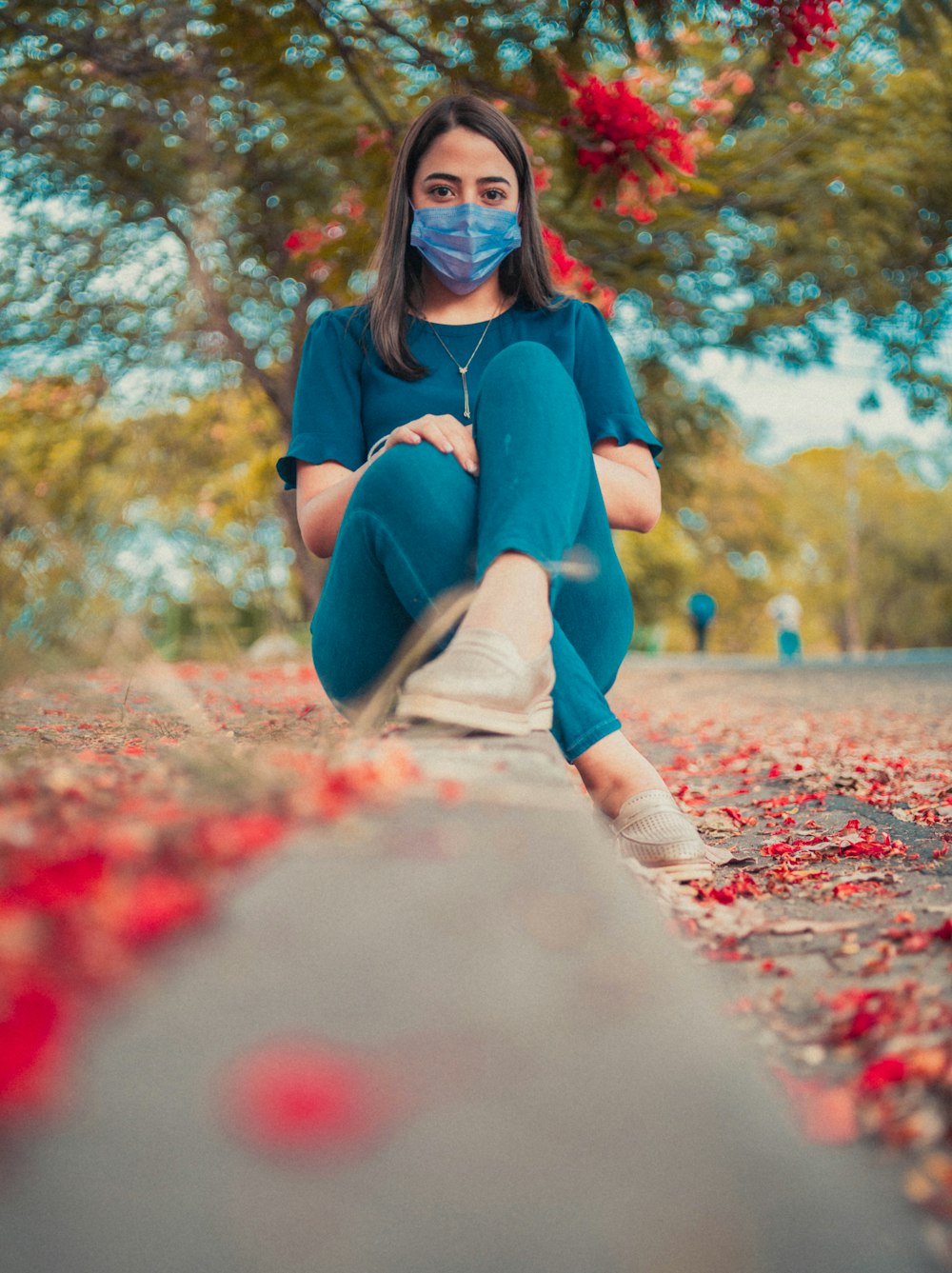 a woman sitting on a curb wearing a face mask