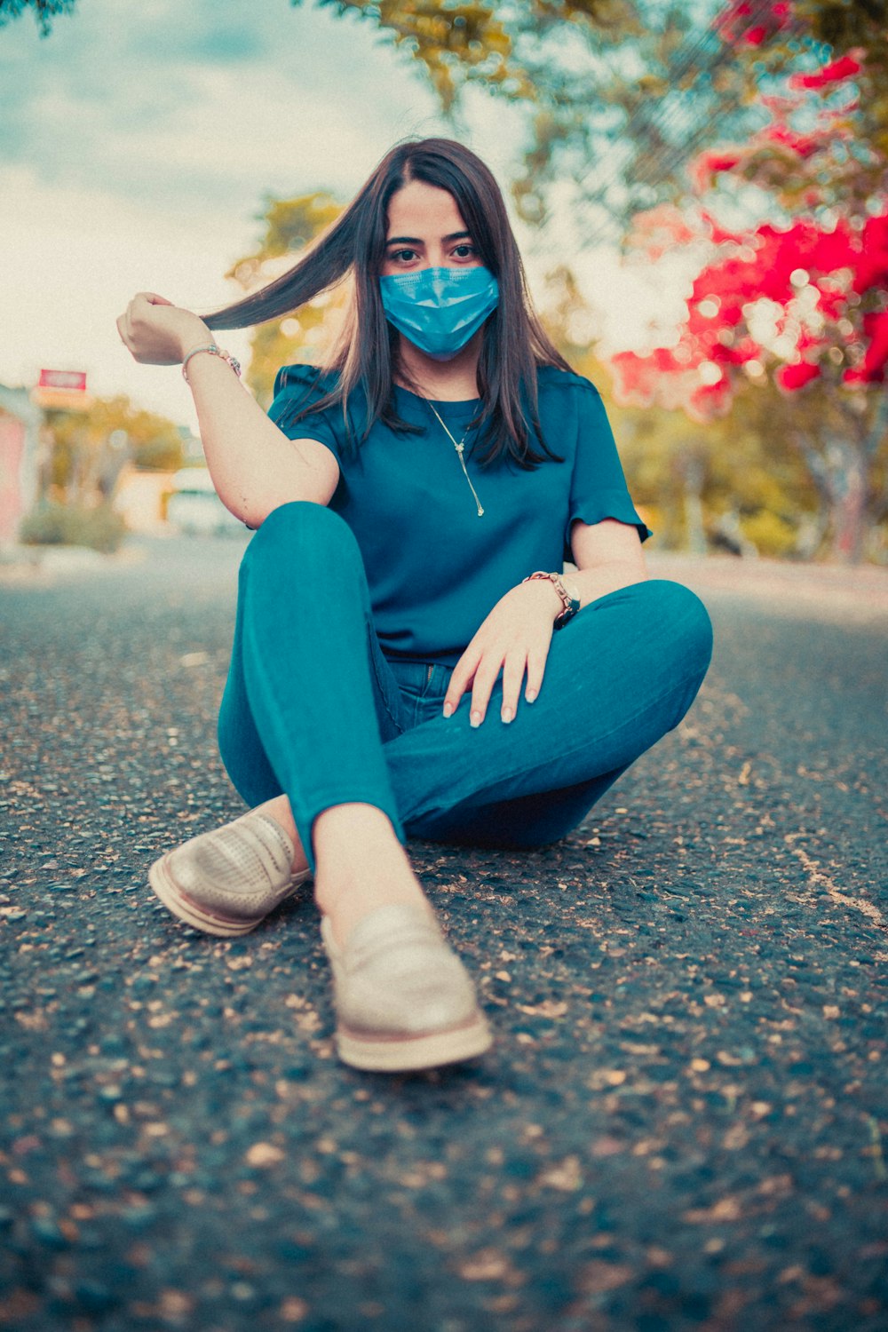 a woman wearing a face mask sitting on the street