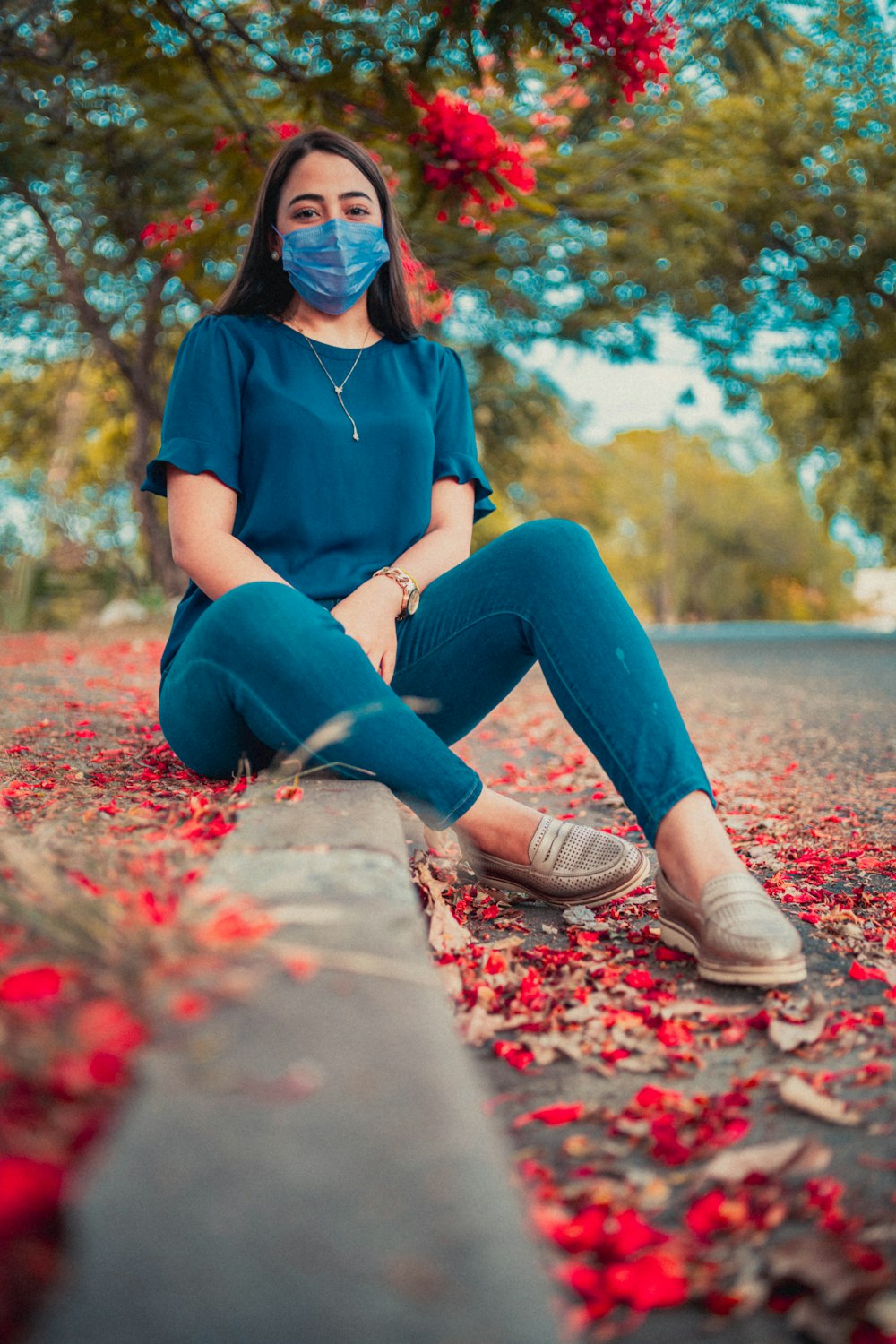 a woman wearing a face mask sitting on a curb