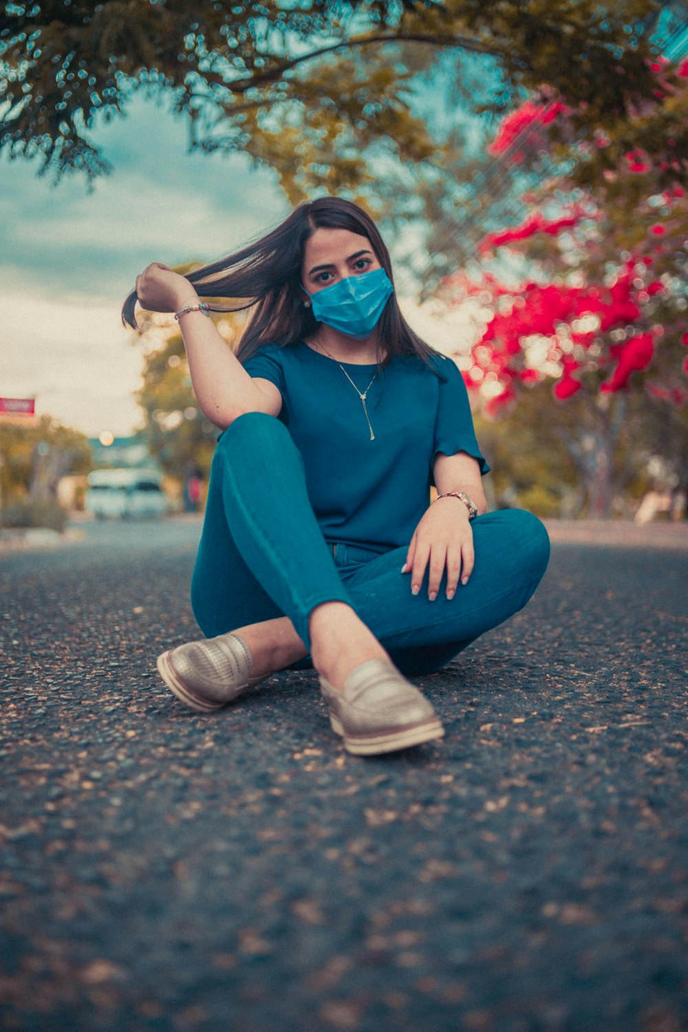 a woman sitting on the ground wearing a face mask