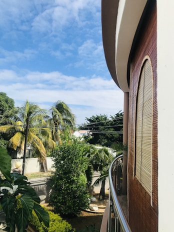 Outdoor balcony featuring stainless steel and glass balustrades overlooking a garden.