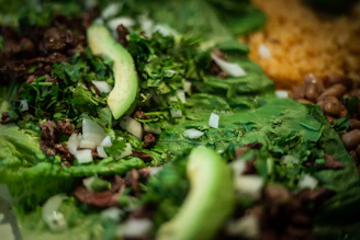 Close-up of golden arepas filled with shredded beef and fresh avocado on a rustic wooden board.