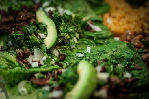 Close-up of golden arepas filled with shredded beef and fresh avocado on a rustic wooden board.