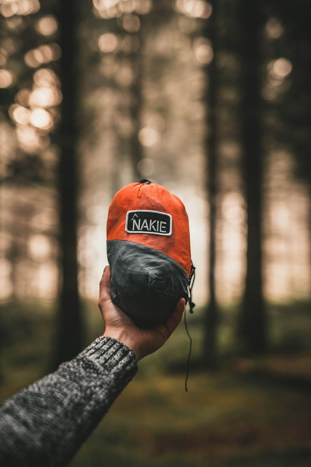 a person holding a hat in front of a forest