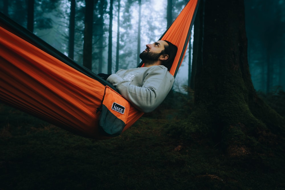 a man laying in a hammock in the woods