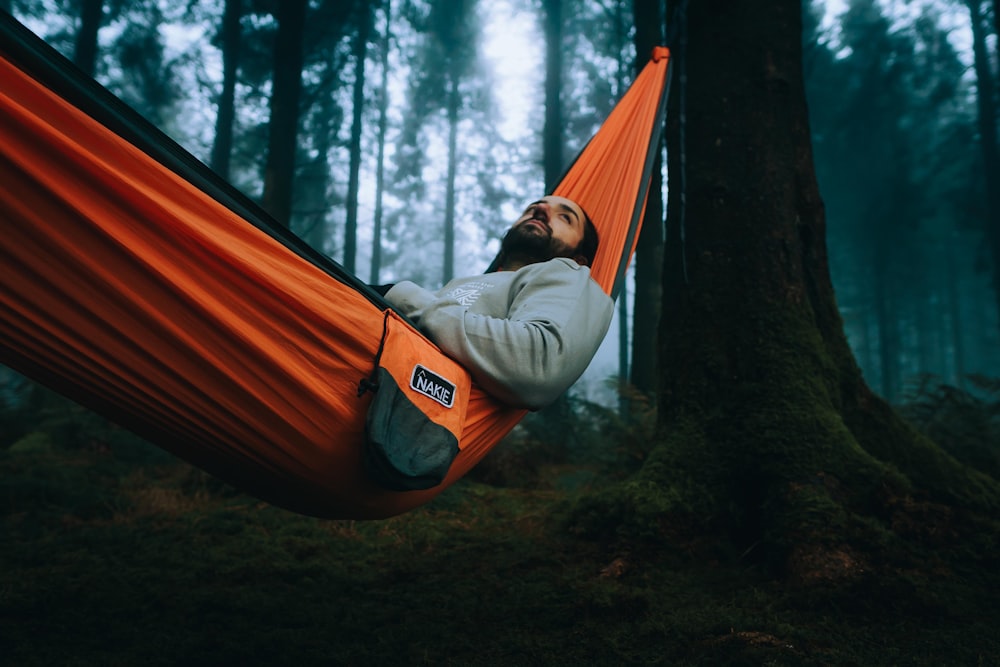 a man laying in a hammock in the woods