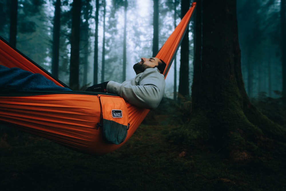 a man laying in a hammock in the woods