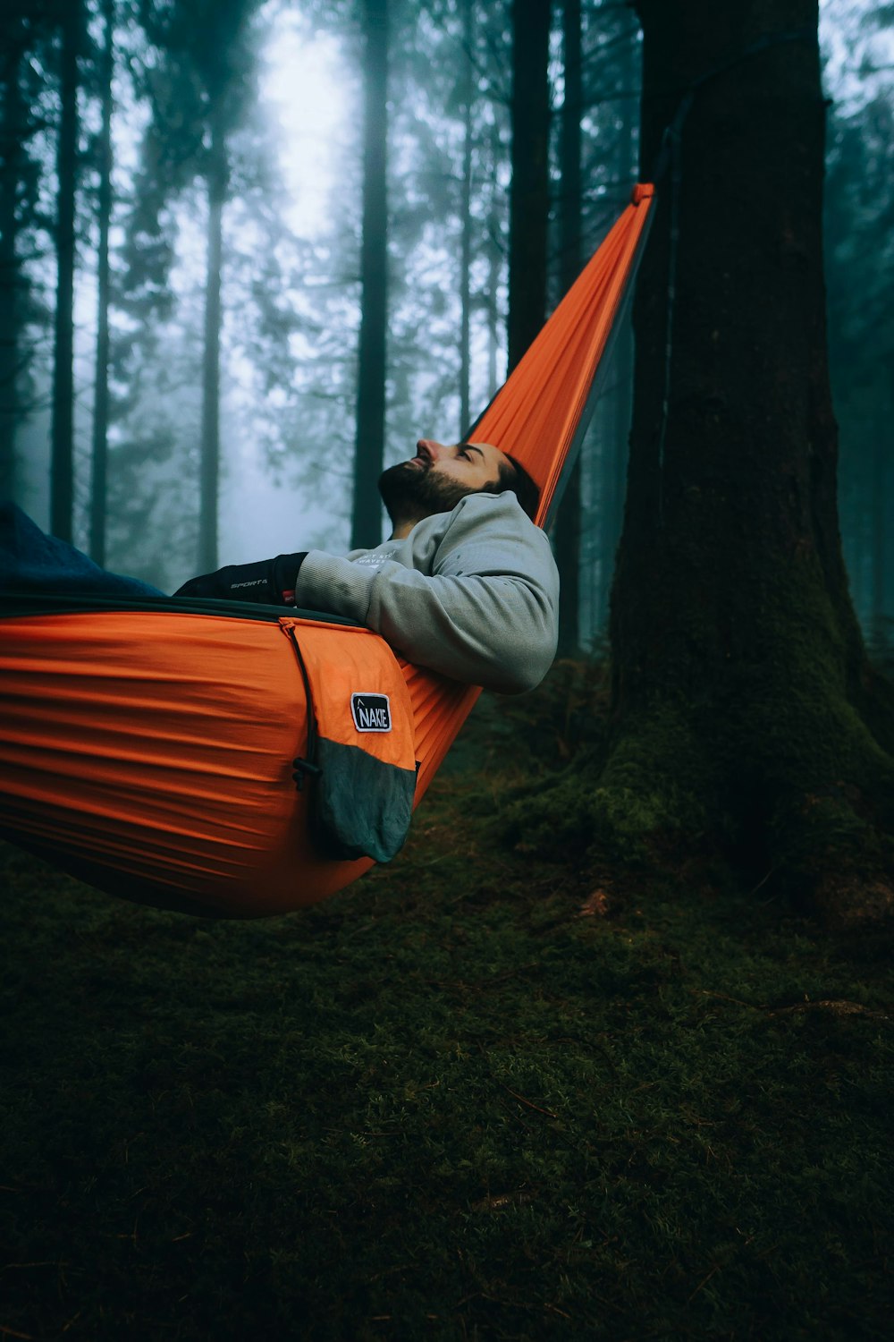 a man laying in a hammock in the woods