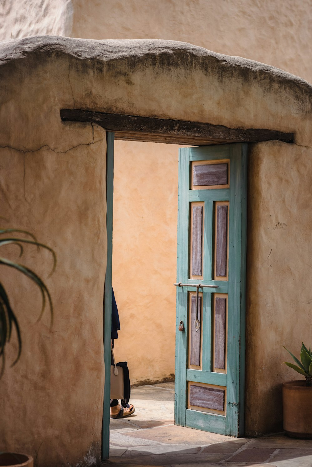 a blue door is open to a tan building