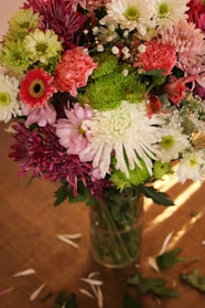 A vibrant bouquet of mixed seasonal flowers in a rustic vase on a wooden table
