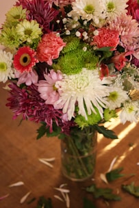 A vibrant bouquet of mixed seasonal flowers in a rustic vase on a wooden table