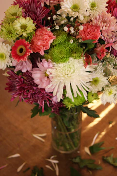A vibrant bouquet of freshly cut flowers displayed in a stylish glass vase on a wooden table.
