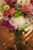 A vibrant bouquet of mixed flowers arranged in a clear glass vase on a wooden table.