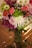 A vibrant bouquet of mixed flowers arranged in a clear glass vase on a wooden table.