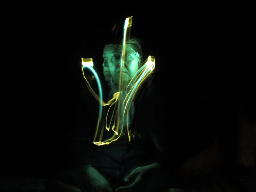 a man sitting in the dark with a light painting on his face