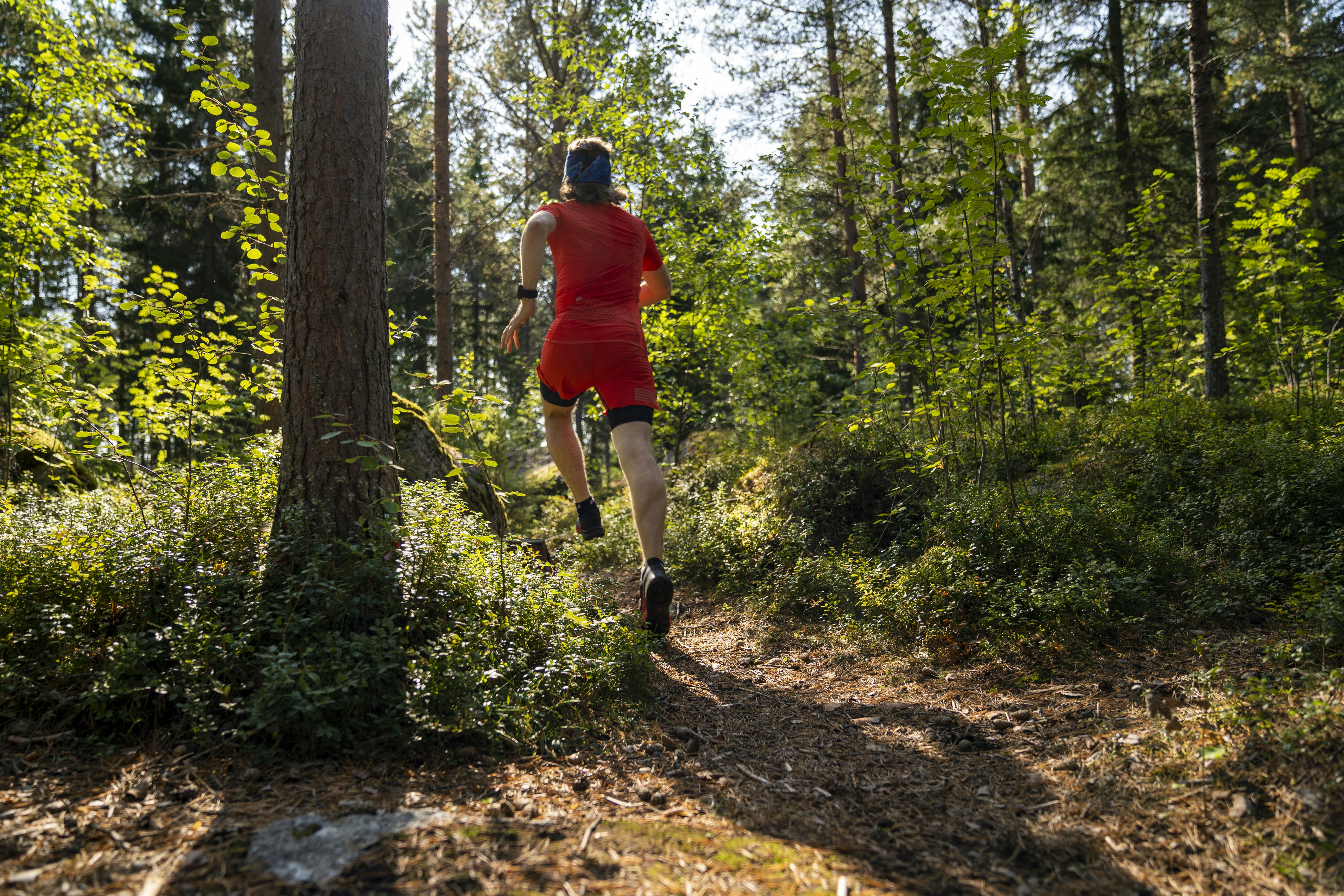 a man in red running through a forest