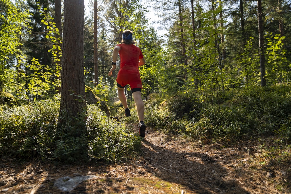 a man in red running through a forest