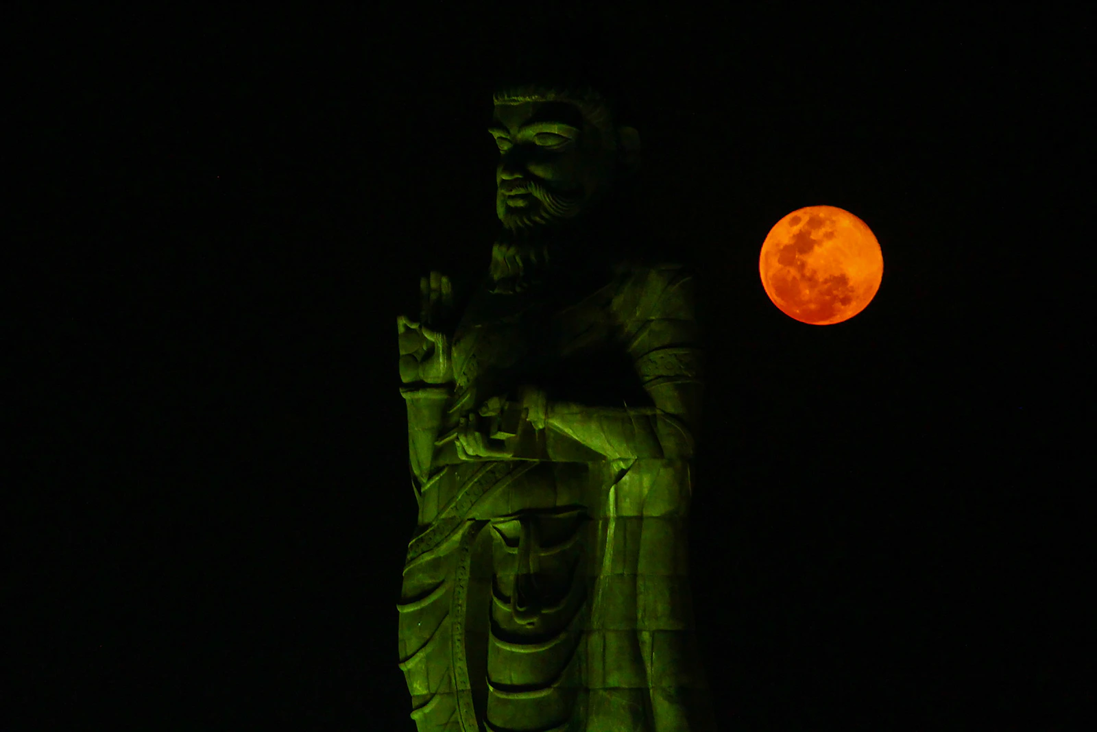 A figure silhouetted against a red moon.