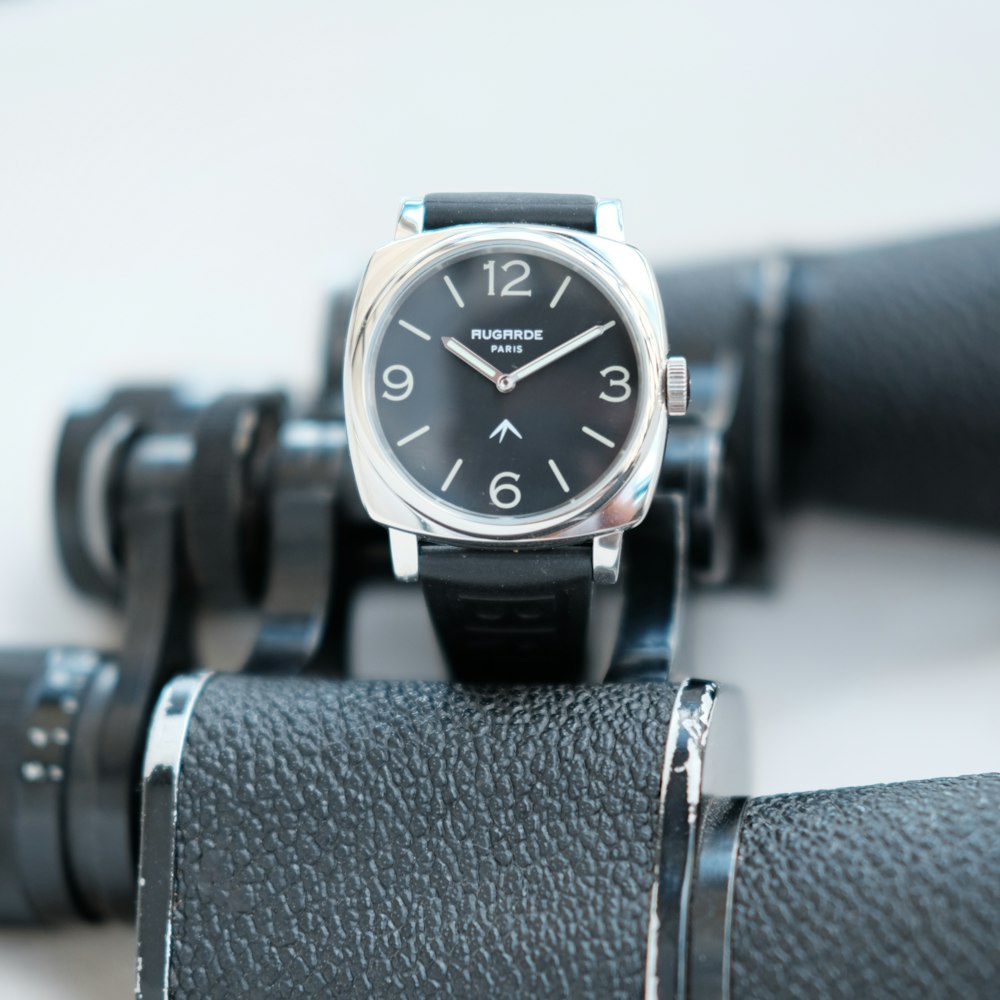 a watch sitting on top of a black leather belt