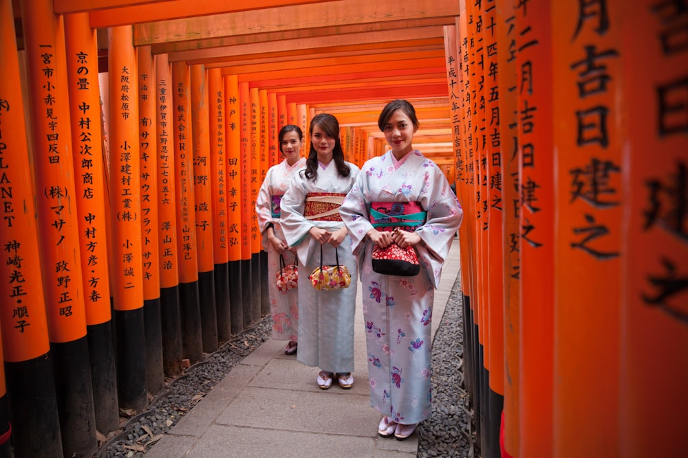 a group of women standing next to each other in front of orange tori tori tori