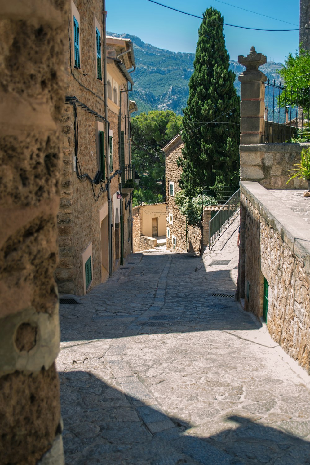 a narrow street with stone buildings and a stone fence