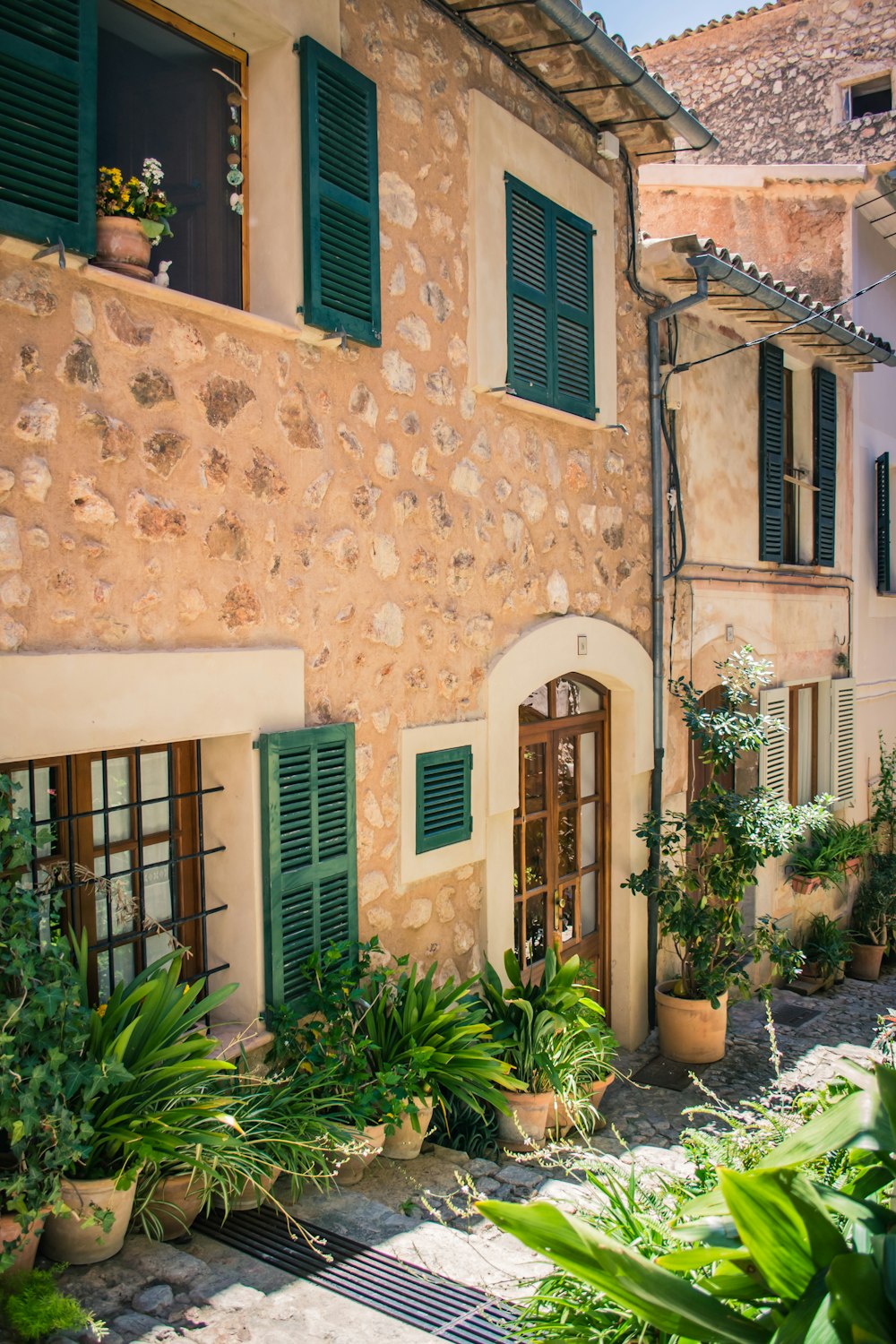 a stone building with green shutters and plants