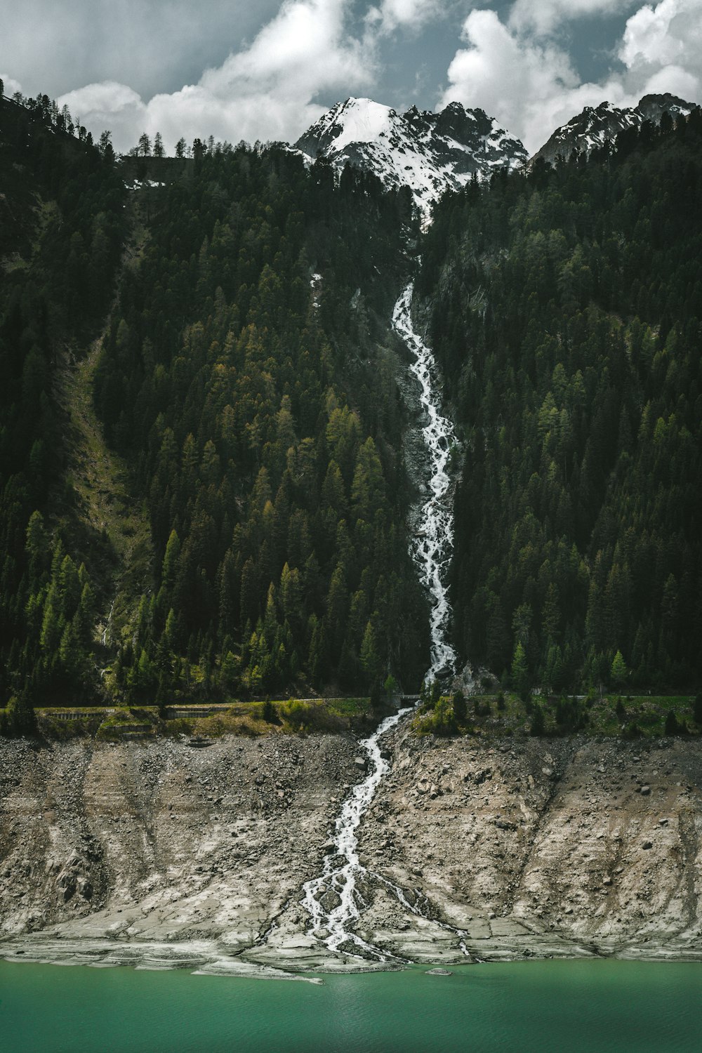 a waterfall flowing into a lake surrounded by trees