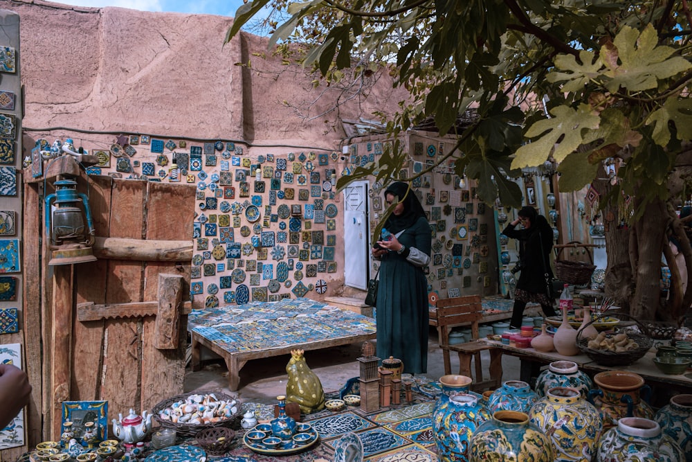 a woman standing in a room filled with pottery