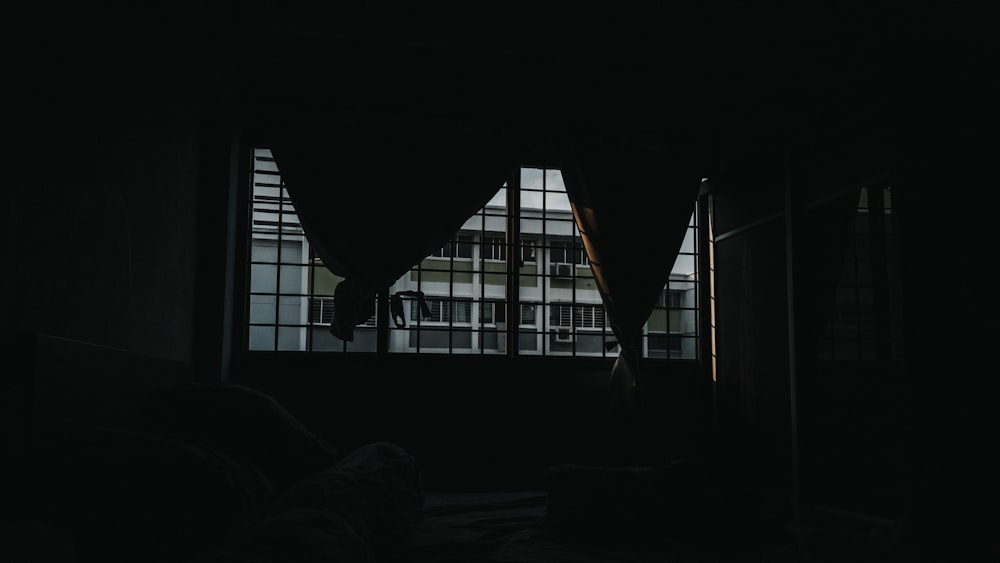 a dark room with a window and a curtain