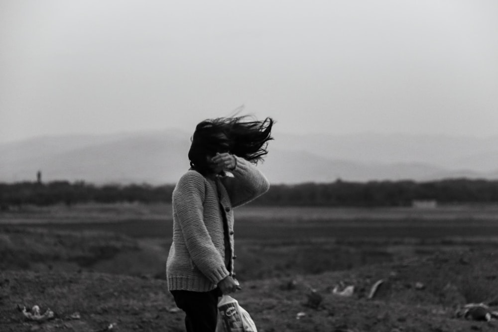 a black and white photo of a woman with her hair blowing in the wind