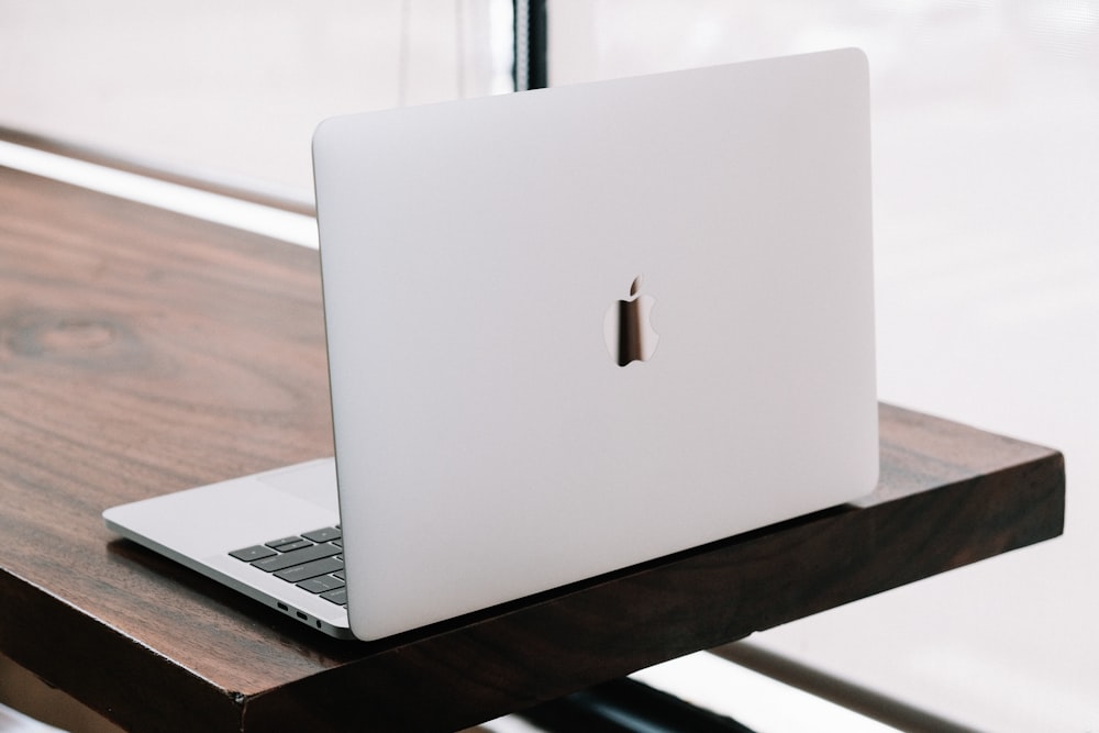 a white apple laptop sitting on top of a wooden desk