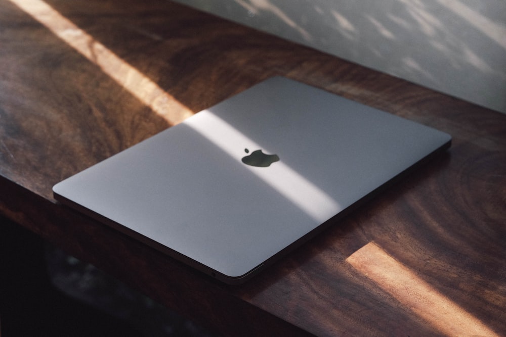 an apple laptop sitting on top of a wooden table