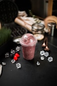 a smoothie in a plastic cup surrounded by ice cubes
