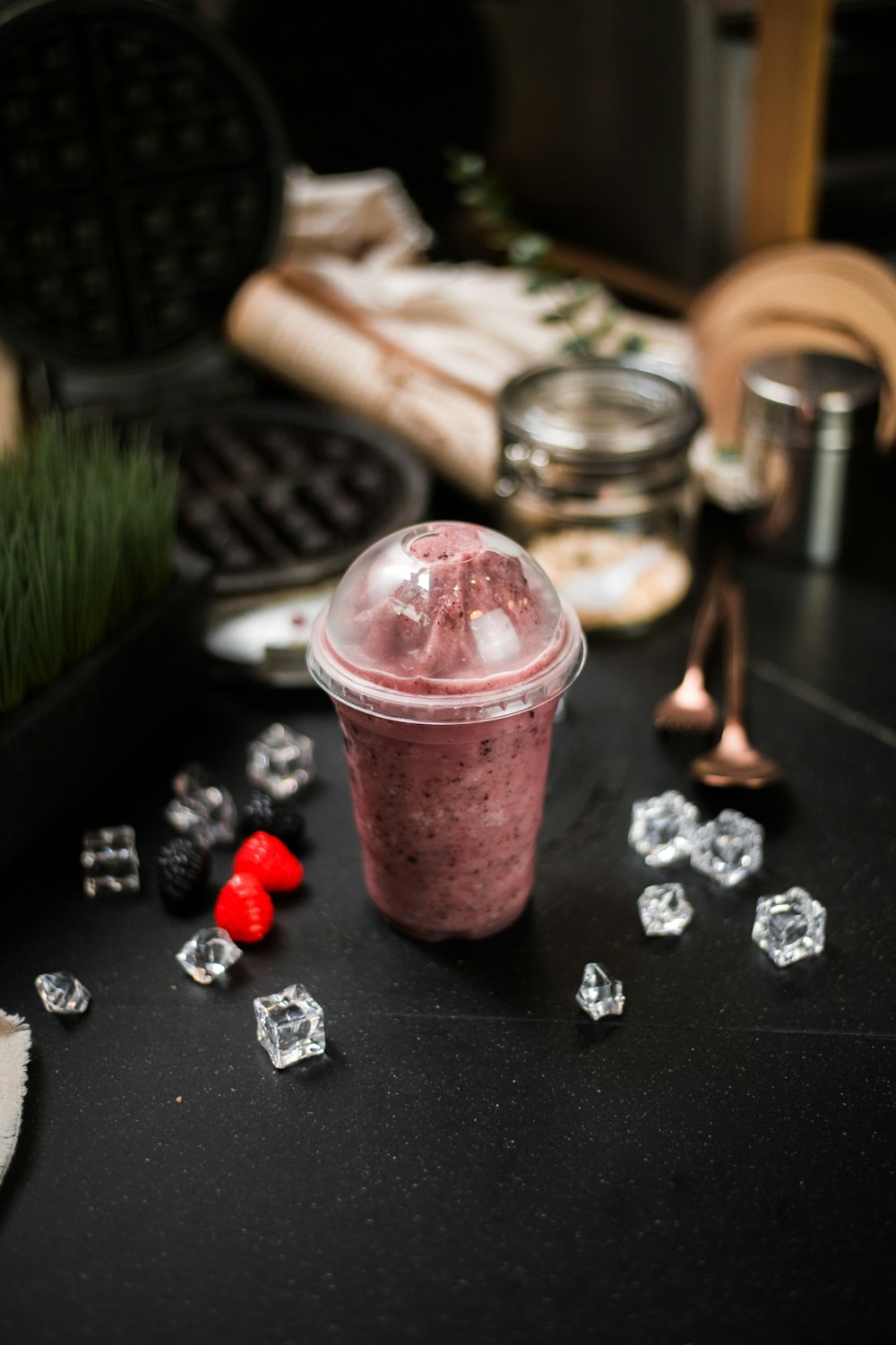 a smoothie in a plastic cup surrounded by ice cubes