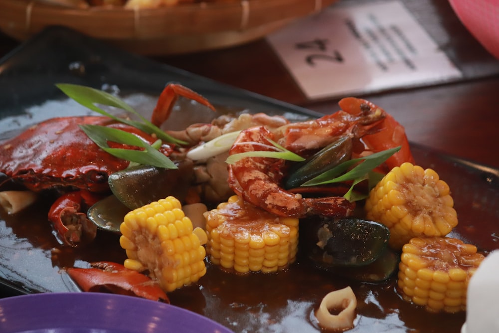 a plate of food with a crab and corn on the cob