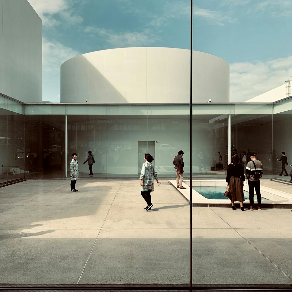 um grupo de pessoas em pé ao redor de uma piscina em um edifício