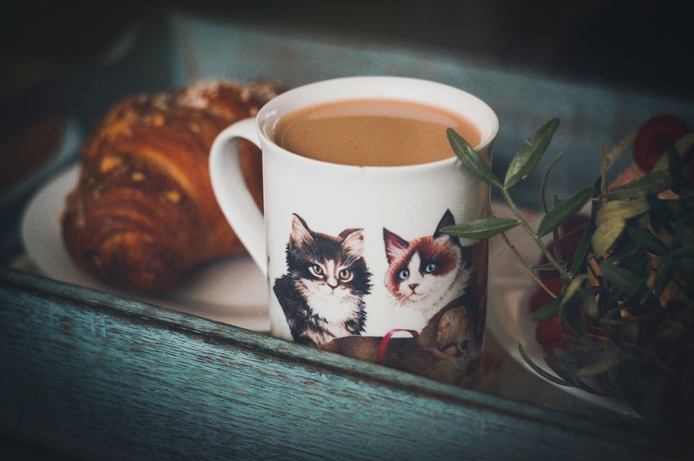 a cup of coffee and a croissant on a tray